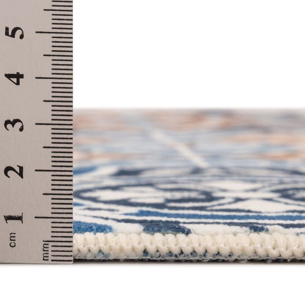 Florhöhe eines gemusterten Teppichs gemessen mit einem Lineal, circa 5 Millimeter.