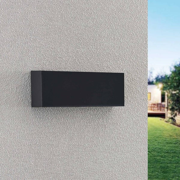 Moderne rechteckige Außenwandleuchte in Schwarz an einer strukturierten Hauswand im Außenbereich.