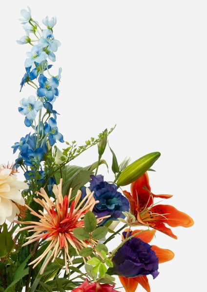 Beistelltisch mit zwei hellen Holzschubladen, bunte Blumensträuße in verschiedenen Vasen, goldene Gießkanne und dekorative Affenfigur.