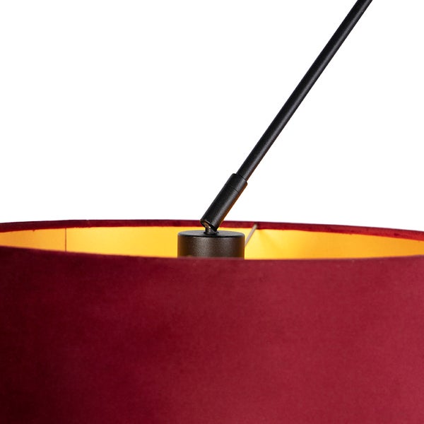 Detailansicht einer Lampe mit rotem Samtschirm, goldfarbener Innenseite und schwarzem Metallarm.