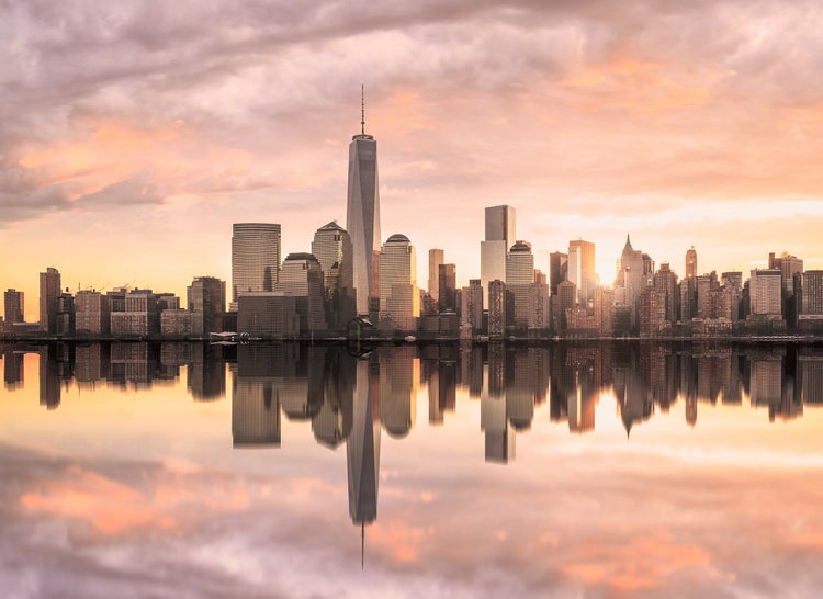 Fototapete mit Skyline von New York, One World Trade Center und Spiegelung im Wasser bei Sonnenuntergang.