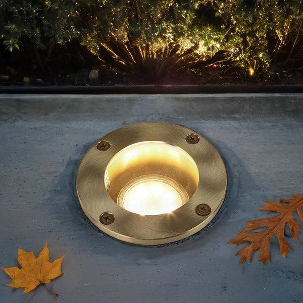 Bodeneinbaustrahler aus Metall mit Blättern auf Betonoberfläche