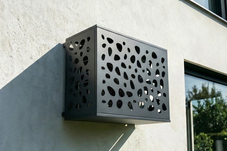 Metallverkleidung für Klimaanlage mit Lochmuster an einer Hauswand