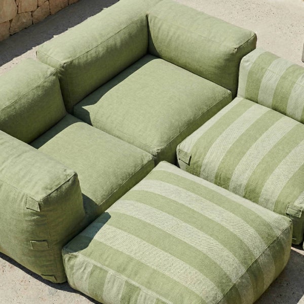 Modulares Garten-Lounge-Set mit zwei Sesseln und zwei Hockern in Grün und gestreift aus wetterfestem Textilgewebe auf einer hellen Terrasse.