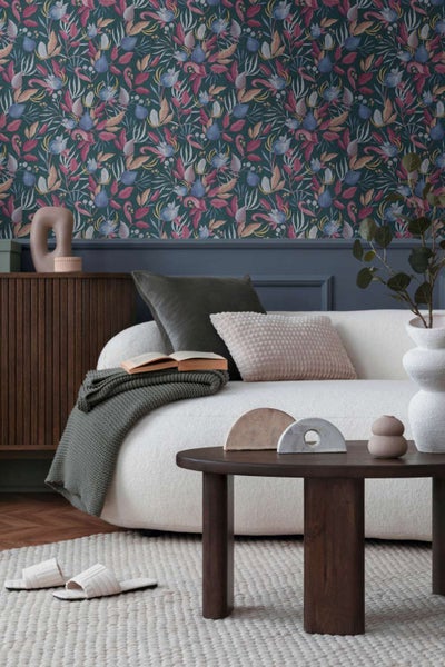 Wohnzimmer mit dunkler Blumentapete, helles Sofa, Couchtisch aus Holz, dekorative Elemente und Teppich in einem modernen, gemütlichen Interieur.