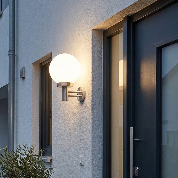 Außenwandleuchte mit kugelförmigem Glas und Metallarm, montiert an einer strukturierten Fassade neben einer Tür.