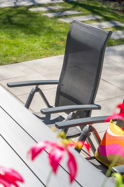 Verstellbarer Gartenstuhl Hochlehner aus Aluminium mit Textilgewebe auf einer Terrasse an einem Gartentisch.