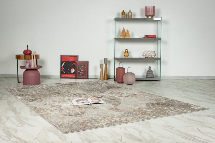 Wohnzimmer mit gemustertem Teppich auf Marmorboden, kombiniert mit einem Regal aus Metall und Glas sowie dekorativen Wohnaccessoires.