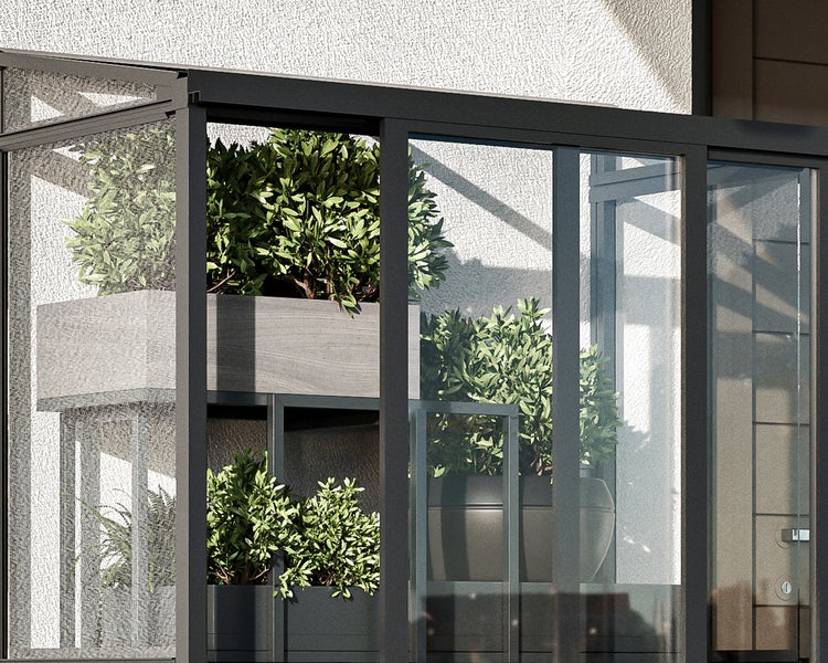 Detailansicht einer Balkonverglasung mit dunkelgrauem Aluminiumrahmen und Glasscheiben vor grünen Pflanzen in Pflanzgefäßen.