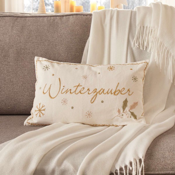 Dekokissen mit Winterzauber-Schriftzug und Schneeflocken auf Sofa