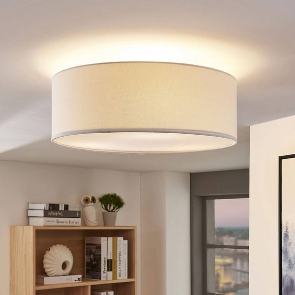 Moderne Deckenleuchte mit rundem Textilschirm in einem hellen, organisierten Wohnraum über einem Holzregal mit Büchern und Dekoration.