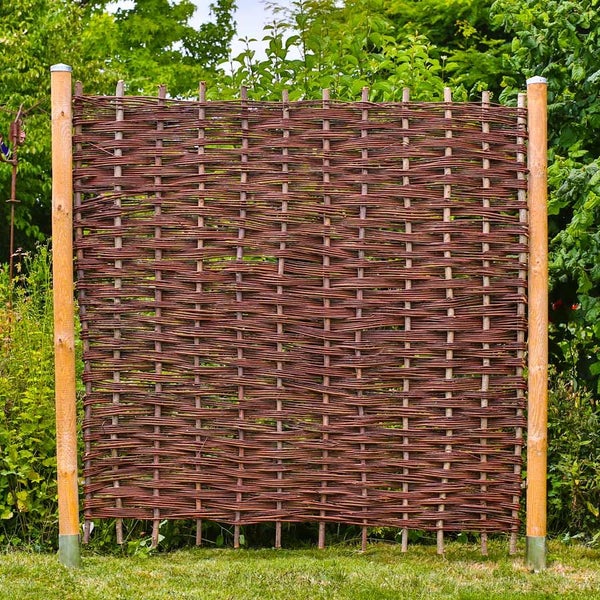 Geflochtener Weidenzaun mit Holzpfosten als Sichtschutz im Garten.