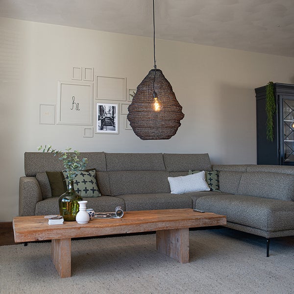 Wohnzimmer mit Ecksofa, Holztisch und geflochtener Hängelampe