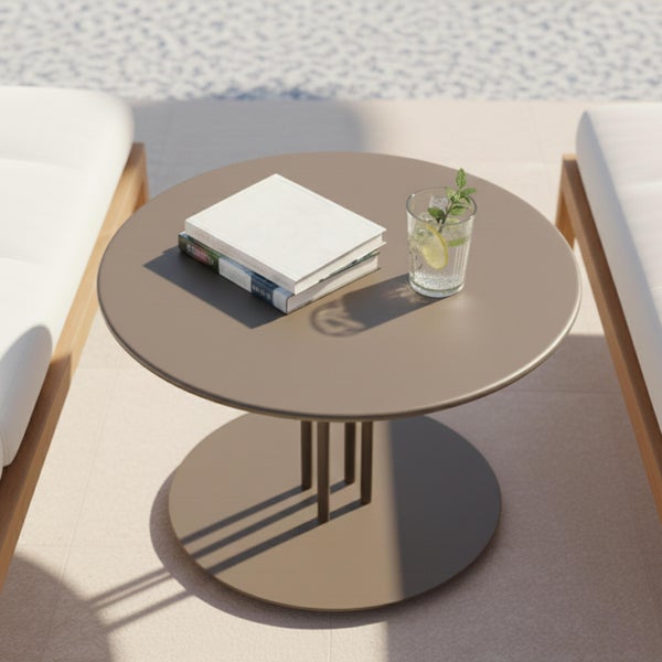 Runder Beistelltisch aus Metall in Taupe auf einer hellen Terrasse zwischen modernen Loungesesseln mit weißen Polstern.