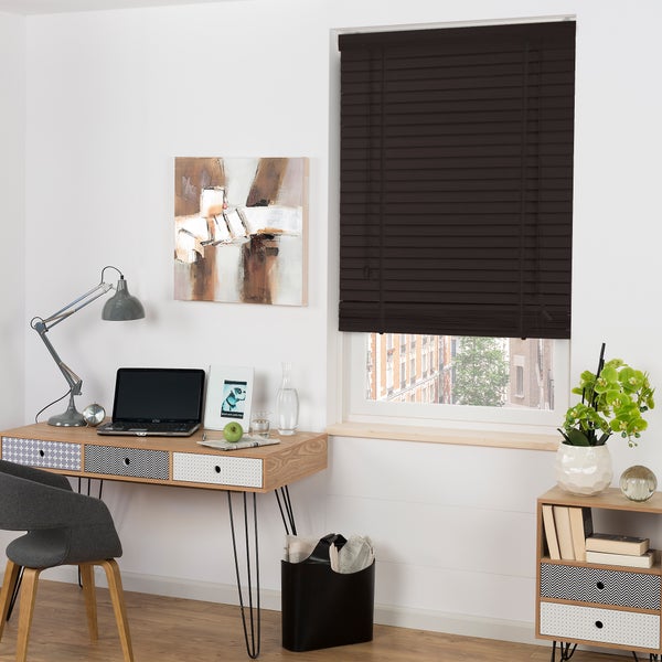 Arbeitszimmer mit Schreibtisch, Stuhl, Regal und geschlossenem, dunklem Holzjalousie vor dem Fenster.