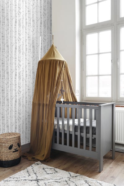 Helles Kinderzimmer mit grauem Kinderbett und Baldachin sowie gemusterter Tapete