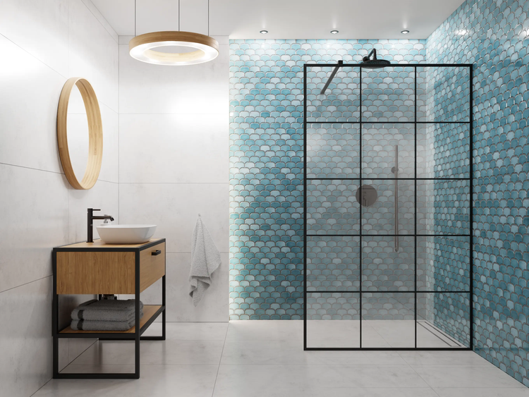 Modernes, helles Badezimmer mit blauen Mosaikfliesen in Schuppenoptik, begehbarer Dusche mit schwarzem Rahmen, Holzwaschtisch und rundem Spiegel.