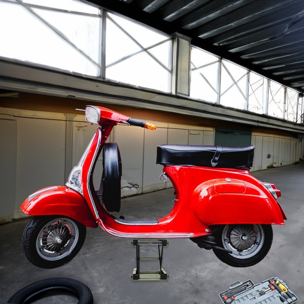 Ein roter Roller auf einem Heber für die Wartung in einer Werkstatt mit einem Werkzeugkasten.