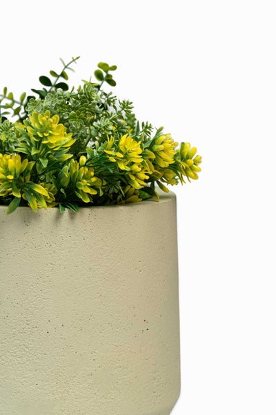 Künstliche Pflanze mit gelben Blüten und grünen Blättern in einem strukturierten, zylindrischen Topf.