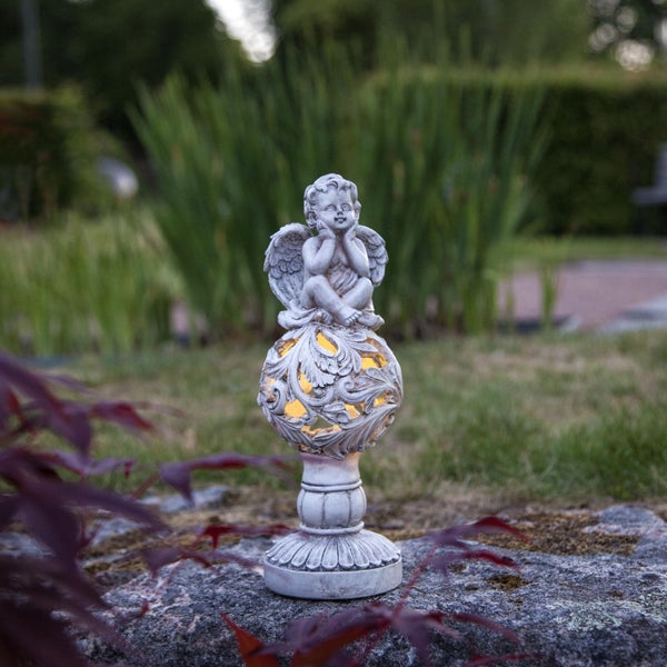 Dekorative Gartenfigur mit Engel auf einer Kugel mit Blattmuster, platziert im Freien