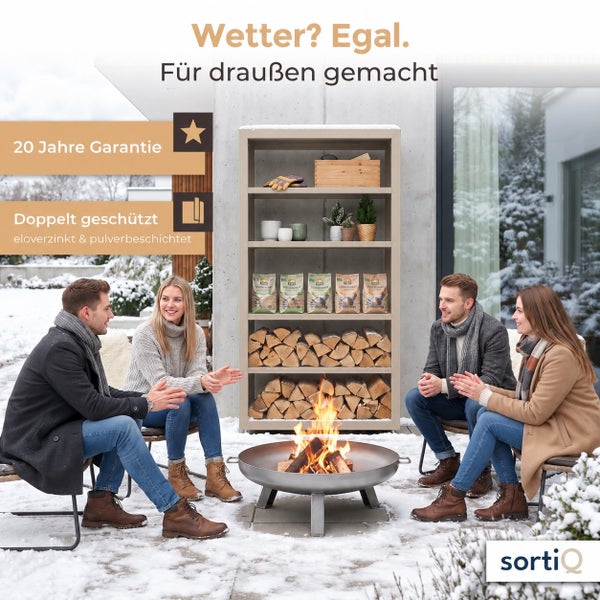 Ein SortiQ Metallregal mit Kaminholz und Dekorationsartikeln steht im verschneiten Garten, während vier Personen vor einer Feuerschale sitzen.
