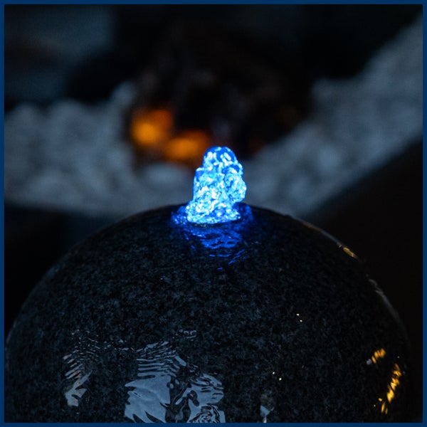 Kugelbrunnen aus Granit mit blauer LED-Beleuchtung und sprudelndem Wasser.