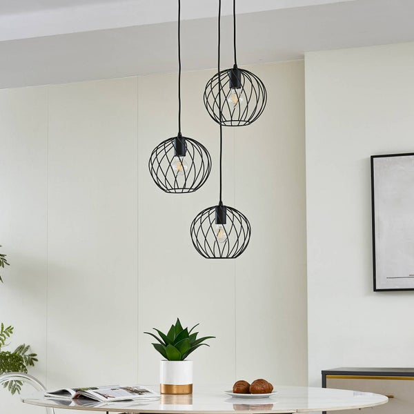 Drei Pendelleuchten mit kugelförmigen Lampenschirmen aus Metall über einem Esstisch.