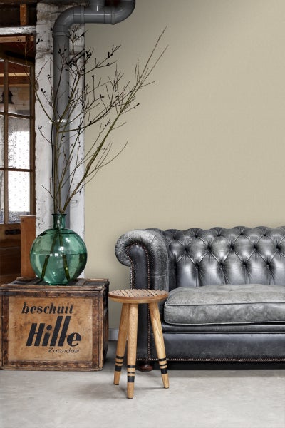 Wohnzimmer mit Chesterfield Sofa, Holzhocker, Weinflasche in grüner Vase und dekorativen Zweigen