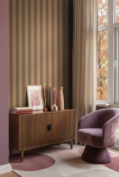 Wohnzimmer mit vertikal gestreifter Tapete, einem hölzernen Sideboard und einem lila Sessel.