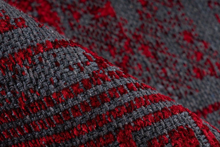 Nahaufnahme eines gewebten Teppichs mit dunkelgrauer Basis und erhobenen roten Strukturmustern.