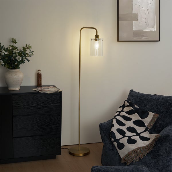 Stehlampe mit Glasschirm neben Kommode und Sessel im Wohnzimmer.