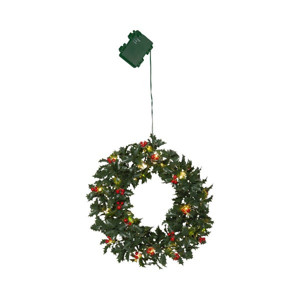 Weihnachtliche Szene mit Stechpalmenkranz und -girlande auf einer Holzbank mit Birkenstämmen