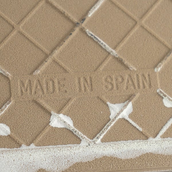 Rückseite einer Fliese mit eingeprägtem Herkunftshinweis Made in Spain und gitterartiger Struktur