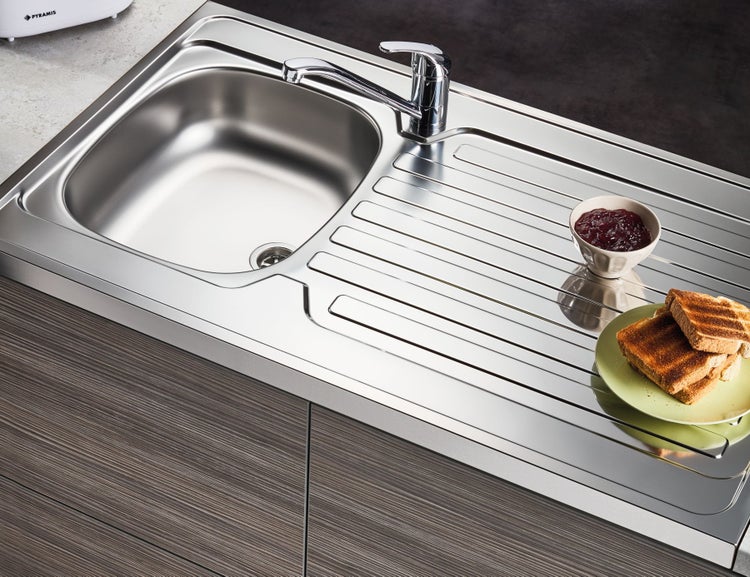 Spüle aus Edelstahl mit Abtropffläche und Armatur, dazu Toast und Marmelade