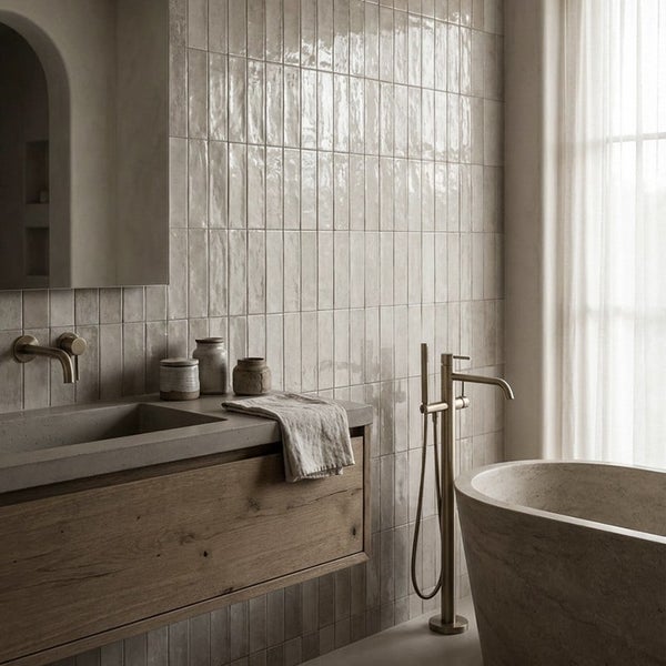 Modernes Badezimmer mit Wandfliesen im Hochformat, Waschbecken aus Beton, Holzunterschrank und freistehender Badewanne mit Armatur in Metalloptik.