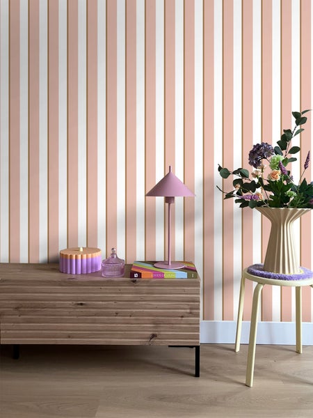 Innenraum mit Kommode, Tischleuchte, Dekoration und gestreifter Tapete