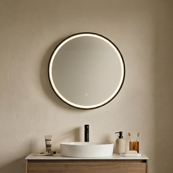 Badezimmer mit rundem Spiegel mit Beleuchtung, Waschbecken und Armaturen auf einem Waschtisch