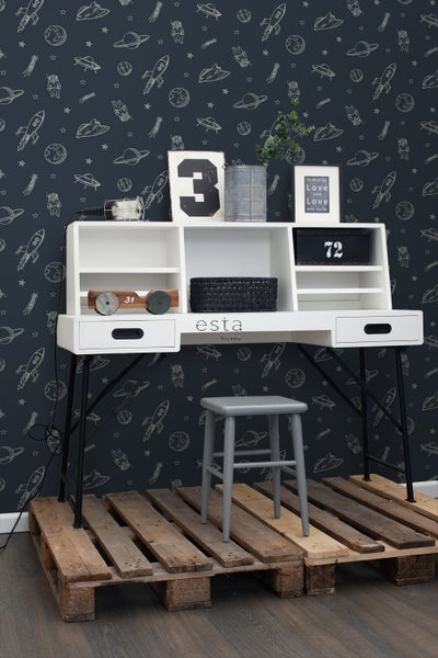Kinderzimmer mit weißem Schreibtisch, schwarzem Metallgestell und grauem Hocker auf Holzpaletten