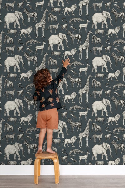 Tapete mit Tiermuster und Kind auf einem Hocker