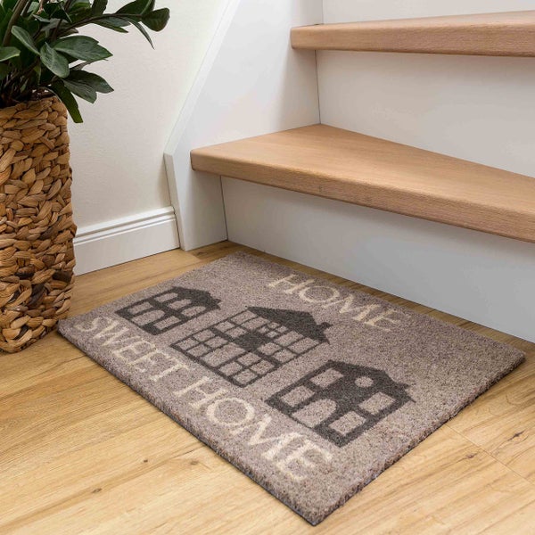 Fußmatte mit Hausmotiv und Schriftzug Home Sweet Home vor einer Treppe und einer Zimmerpflanze.