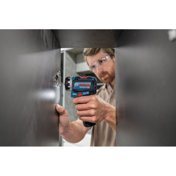 Handwerker mit Schutzbrille verschraubt ein Scharnier an einem Schrank mit einem Bosch Professional Akku-Bohrschrauber.