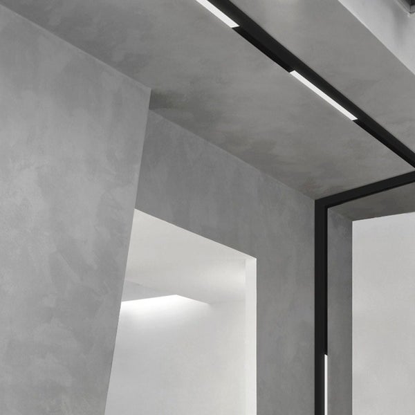 Detailaufnahme eines modern gestalteten Innenraums mit Betonwänden und integrierter Beleuchtung.