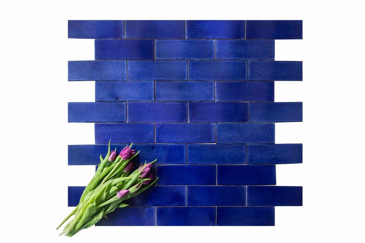 Blaue Wandfliesen in Ziegeloptik mit einem Strauß Tulpen.