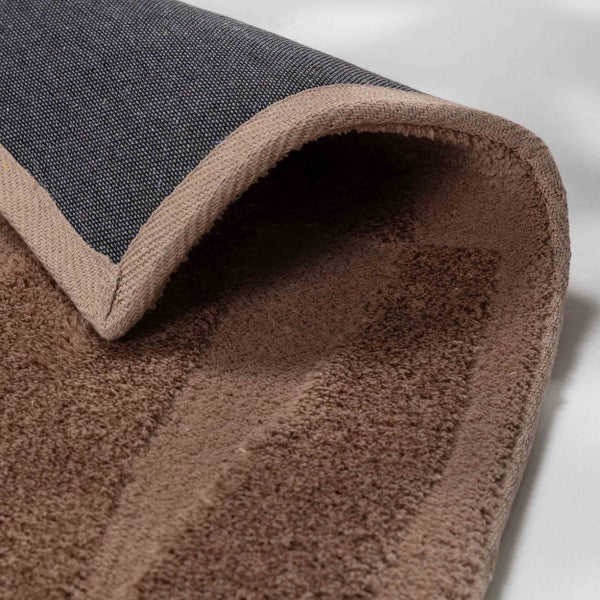 Detailansicht eines Teppichs mit weichem Flor, gewebter Einfassung und strukturierter Rückseite.