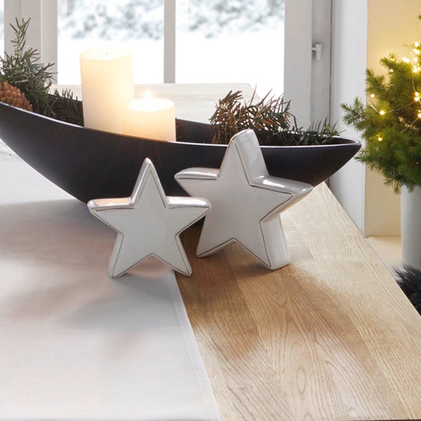 Dekoration mit Kerzen, Tannenzweigen und Sternfiguren auf einem Tisch