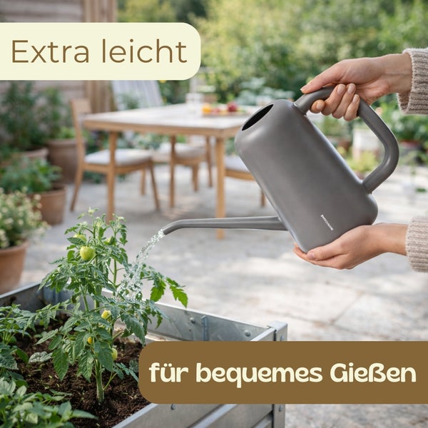 Eine Person gießt bequem eine Pflanze in einem Hochbeet mit einer extra leichten grauen Gießkanne im Garten.