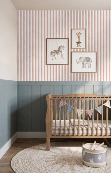 Kinderzimmer mit vertikal gestreifter Tapete, Wandpaneelen in Holzoptik, einem Babybett aus Holz, einem runden Webteppich und Wandbildern.