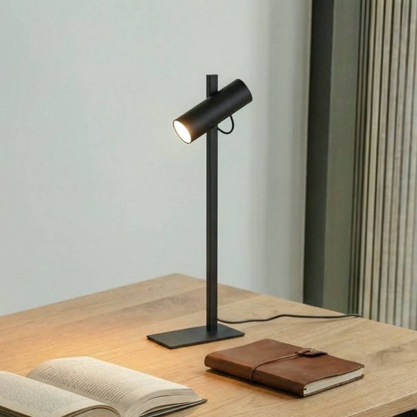 Schreibtisch mit schwarzer Tischleuchte und geöffnetem Buch