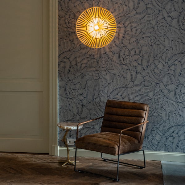 Innenaufnahme mit Sessel, Beistelltisch, Wandleuchte und floral gemusterter Tapete