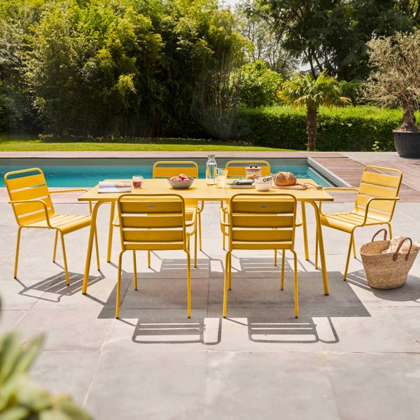 Moderne Gartenmöbel-Sitzgruppe aus gelbem Metall auf einer hellen Terrasse am Pool, bestehend aus einem Tisch und sechs Stühlen.